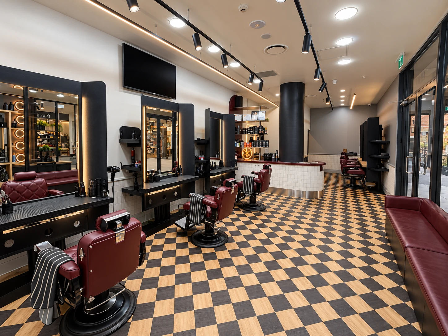The welcoming interior of Barber Embassy Granville, with burgundy chairs and illuminated mirrors
